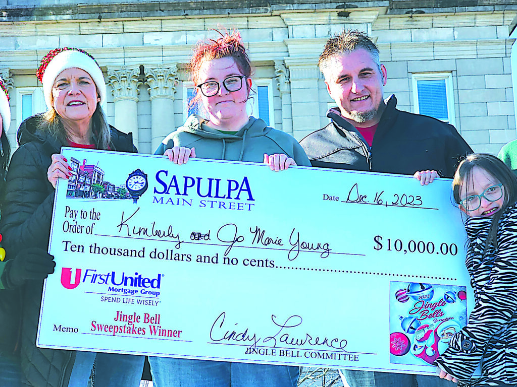 CHARLES BETZLER PHOTOS WINNER Sapulpa Main Street Director Cindy Lawerence (left) presents a check for $10,000 to the Jingle Bell Grand Prize winner Kimberly Young (middle). The winning ticket number came from Alternative Health Care Dispensary.