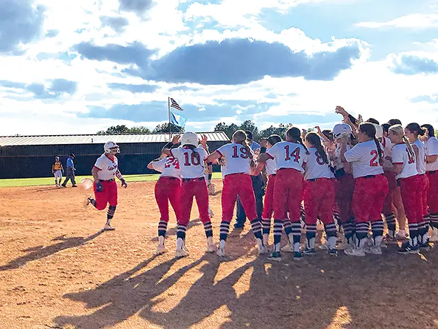 JOHN TRANCHINA PHOTOS KIEFER SENIOR LIL BACON (left) trots home into the waiting arms of her Lady Trojan teammates after delivering a grand slam home run to center field that gave Kiefer an 8-3 lead in the fourth inning, en route to a 9-5 triumph over Westville Tuesday night.