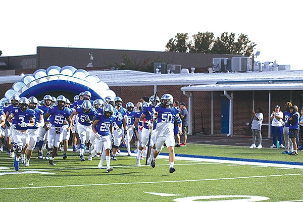 RUNNING OUT OF THE TUNNEL The Chieftains were ready to go, as senior Tait Tummons (far right, 50) carries the spear leading the team out on Friday night before their dominating 58-0 victory over Putnam City West.