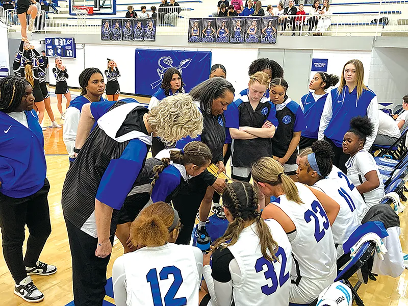 SAPULPA COACH DARLEAN CALIP (center) diagrams a play on her clipboard during the break after the first quarter Tuesday night at the Chieftain Center.