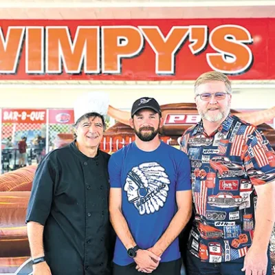 CHARLES BETZLER PHOTOS MIKE NAIFEH, owner of Wimpy’s Sandwich Shoppe (left), Sapulpa wrestling coach Cody Fuller (center) and Jeff Schwickerath smile for the camera.